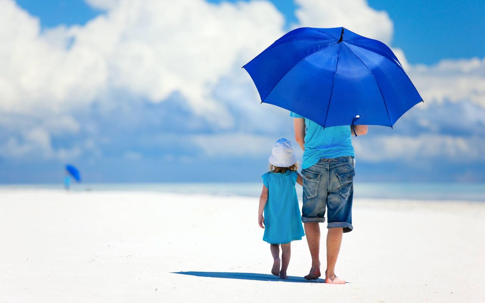 parent and child with parasol on the beach