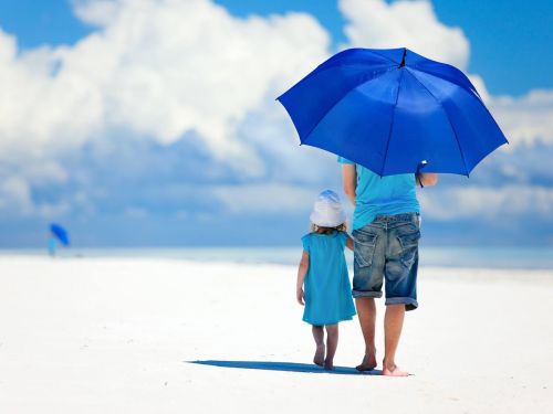 parent and child with parasol on the beach