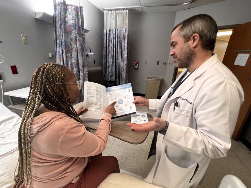 Jacob Wetsell, PharmD, BCPS reviews medication with a patient at Nashville General 