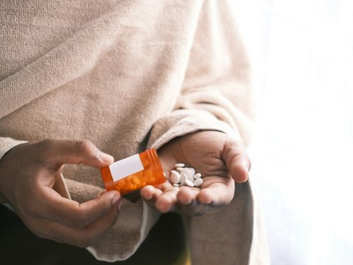man's hand with pills spilled out of the container .