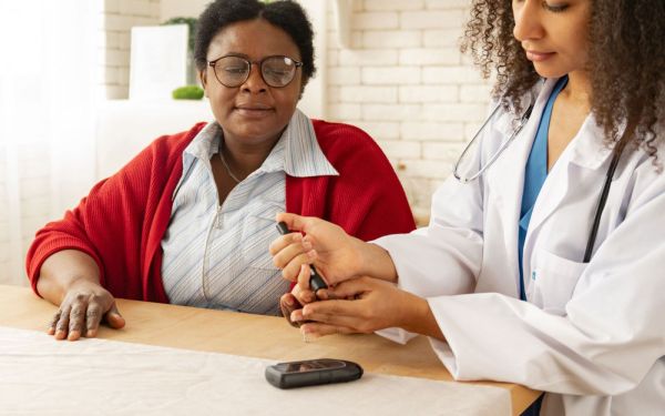 nurse checking blood sugar of elderly woman