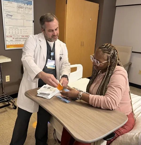 Jacob Wetsell, PharmD, BCPS reviews medication with a patient.