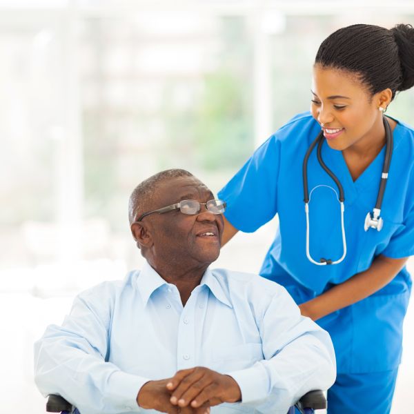Friendly physician in scrubs helps elderly patient in a wheelchair