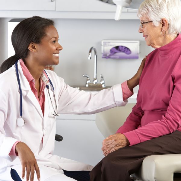 Young female physician in exam room with elderly patient