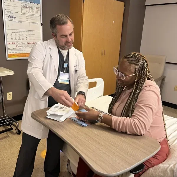 Jacob Wetsell, PharmD, BCPS reviews medication with a patient.
